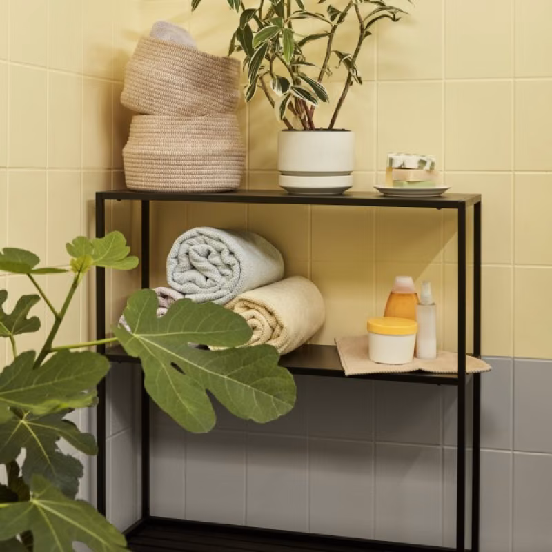 black shelf in front of yellow bathroom tile wall